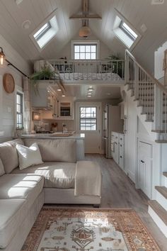 a living room filled with furniture next to a kitchen and stairway leading up to the second floor