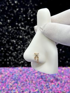 a close up of a person's hand holding a ring on a mannequin head