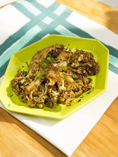 a green plate topped with meat and veggies