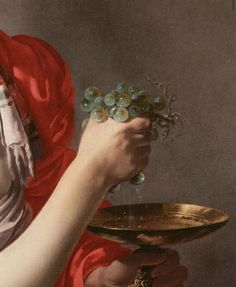 a close up of a person holding a plate with grapes on it and wearing a red dress