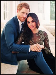 a man and woman sitting on the ground posing for a photo in front of a building