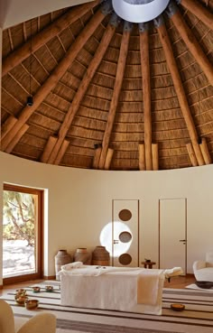 the inside of a large room with a round ceiling made of wood and thatched roof