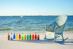 a rocking chair on the beach with bottles in front of it