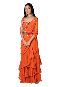 Orange pre-stitched saree with layered ruffles. Paired with floral embroidered blouse and detachable floral embroidered belt.
Component: 3
Embroidered
Neckline: Square
Sleeve Length: Sleeveless
Fabric: Raw Silk, Chiffon
Color: Orange
Embroidered belt - Aza Fashions Fusion Pre-draped Saree With Unstitched Blouse For Diwali, Designer Fusion Pre-draped Saree For Diwali, Festive Fusion Pre-draped Georgette Saree, Designer Draped Georgette Sharara, Festive Fusion Style Pre-draped Georgette Saree, Fusion Style Saree In Georgette With Traditional Drape, Orange Georgette Pre-draped Saree, Fusion Style Pre-draped Saree With Cutdana, Fusion Style Pre-draped Saree With Pallu