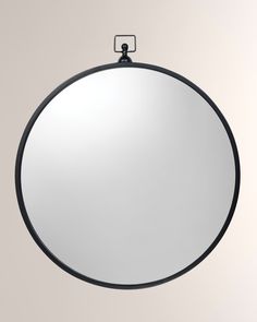 a round mirror hanging on the wall above it's head, with a black frame