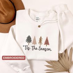 Christmas Tree Embroidered Sweatshirt, Tis The Season, Christmas, Embroidered Christmas Sweatshirt, Embroidery Christmas Gift, Gift for Her Explore our vibrant collection of embroidered clothing and personalized gifts! Before you place your order, check out our easy-to-use color and size charts. Have questions? Reach out to us anytime for expert advice on sizing and color options. We believe in quality, which is why we handpick premium brands like Gildan Softstyle, Circle, and Bella Canvas for o Embroidered Cotton Christmas Sweatshirt, Christmas White Embroidered Tops, Holiday Embroidered Tops For Fall, White Tops With Custom Embroidery For Christmas, Christmas Holiday Embroidered Sweatshirt, Embroidered Christmas Holiday Sweatshirt, Embroidered Christmas Holiday Tops, Holiday Embroidered Tops As Gift, Holiday Cotton Embroidered Tops