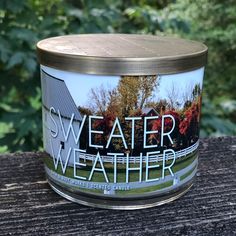 a candle that is sitting on top of a wooden table with trees in the background