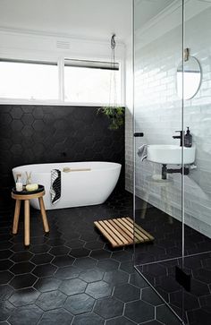 a black and white bathroom with hexagonal tiles on the floor, an oval bathtub in the corner