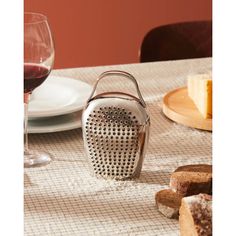 a grater sitting on top of a table next to some bread and wine glasses