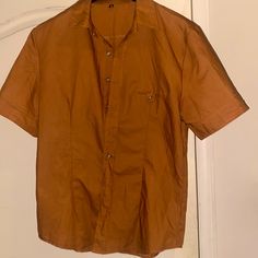 Men's Rust Clay/Burnt Sienna Colored Button Up, Never Worn Before, Size M/L, Front Pocket Just For Decoration Purposes, Also Has Buttons On For Collar And Sleeves. Orange Button-up Shirt With Pockets, Orange Button-up Top With Pockets, Classic Orange Short Sleeve Shirt, Collared Orange Shirt With Buttons, Orange Collared Shirt With Buttons, Orange Cotton Shirt With Pockets, Orange Short Sleeve Tops With Pockets, Orange Button-up Shirt With Button Closure, Orange Short Sleeve Shirt With Buttons