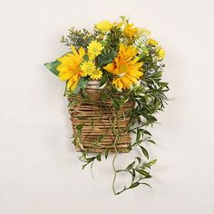 a wicker basket with yellow flowers hanging on the wall