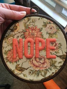 someone is holding up an embroidered hoop with the word nope on it