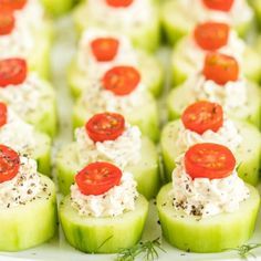 small cucumbers with tomatoes and cream cheese on them are arranged on a white platter