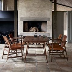 a dining room table with chairs and a fire place in the back wall behind it