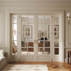 a living room with white furniture and glass doors that lead into the dining room area