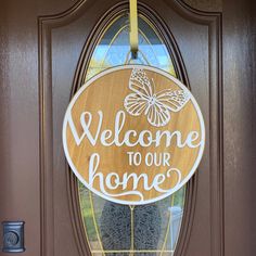 a welcome to our home sign hanging on the front door with a glass pane