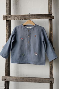 Forest long sleeve unisex shirt with three coconut buttons is made of 100% soft medium weight linen. The shirt is suitable for both girls and boys.  Details: - Choose size in the drop down menu - Colour: Dusty blue - Composition: 100% Oeko-Tex certified linen - Embroidered hedgehog, pine tree, autumn leaves, mushroom, berries, acorn - from both sides (front and back) - Three coconut buttons in the front - Medium weight linen - Unisex  - Relaxed silhouette - Linen care: machine wash gentle; tumbl Casual Embroidered Long Sleeve Tops, Casual Long Sleeve Shirt With Floral Embroidery, Casual Long Sleeve Embroidered Shirt, Relaxed Fit Long Sleeve Shirt With Floral Embroidery, Long Sleeve Shirt With Floral Embroidery And Relaxed Fit, Embroidered Cotton Collared Tops, Blue Long Sleeve Tops With Buttons, Light Blue Cotton Tops With Buttons, Blue Long Sleeve Top With Buttons