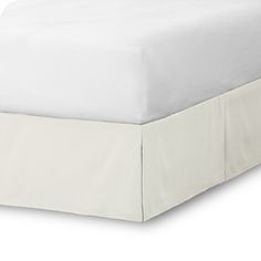 a bed with white sheets and a white cover on it's headboard is shown