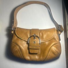 This Is An Authentic Vintage Coach Shoulder Handbag Purse Made Of High-Quality Leather In A Beautiful Brown Color. It Features A Solid Pattern And A Button And Buckle Closure. The Bag Is 11 Inches Wide, 6.7 Inches (17 Cm) High, And 2.4 Inches (6 Cm) Deep, With A Length Of 9.8 Inches (25 Cm). The Strap Drop Ranges From 6.3 To 8.7 Inches (16 To 22 Cm) And Is Made Of Stainless Steel And Leather. The Bag Also Comes With A Coach Charm Accessory. The Interior Lining Is Made Of Brown Fabric, And The Ha Classic Shoulder Bag Satchel With Silver-tone Hardware, Classic Gold Satchel With Branded Hardware, Classic Tote Shoulder Bag With Silver-tone Hardware, Classic Coach Shoulder Bag With Silver-tone Hardware, Vintage Shoulder Bag With Silver-tone Hardware And Double Handle, Coach Leather Shoulder Bag With Handles, Classic Leather Shoulder Bag With Branded Hardware, Vintage Double Handle Shoulder Bag With Silver-tone Hardware, Leather Handheld Bag With Branded Hardware