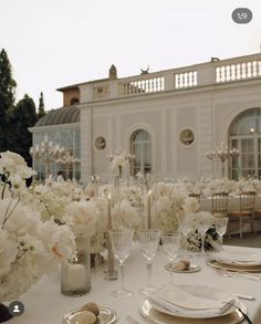 the table is set with white flowers and place settings