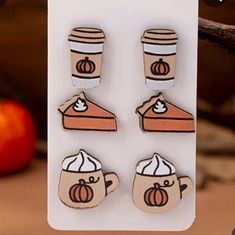 three wooden magnets with coffee and pumpkin designs on them, sitting next to an apple