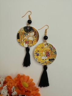 two pairs of earrings with tassels on top of each other next to an orange flower