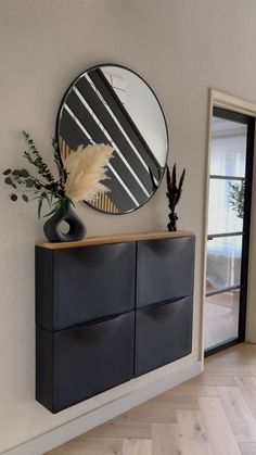 a black cabinet with a round mirror above it