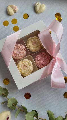 four cupcakes in a white box with pink ribbon and gold confetti