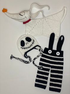 two knitted items are laying next to each other on a white surface, one is wearing a hat and the other has a skull