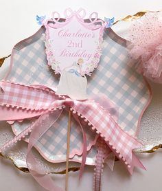 a pink and white cake topper sitting on top of a plate