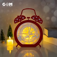 a red alarm clock sitting on top of a table next to a lit christmas tree