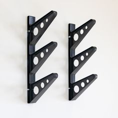 three black brackets are mounted to the wall with holes in each one's side