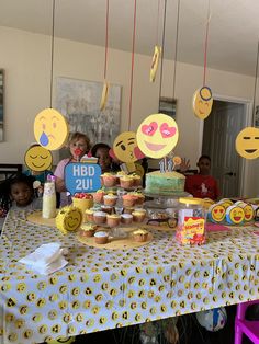 a table topped with lots of cupcakes covered in smiley face cutout decorations