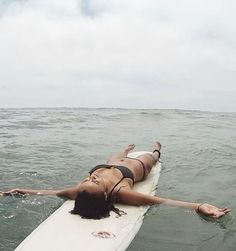 a woman laying on a surfboard in the ocean