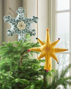 a star ornament hanging from the side of a christmas tree in front of a window