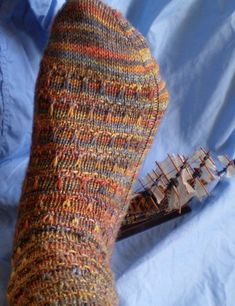 a person's feet with knitted socks next to a model ship on a blue sheet