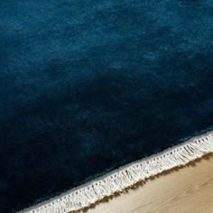 a blue area rug with fringes on the bottom and floor in front of it