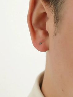 a man wearing a pair of tiny diamond studs on his ear, looking at the camera