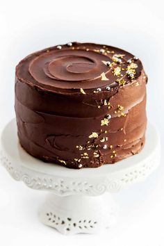 a chocolate cake with gold sprinkles sitting on top of a white plate