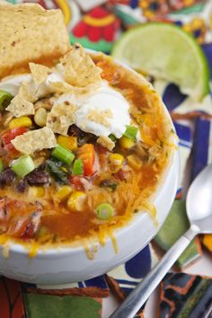 a bowl of mexican soup with tortilla chips and sour cream on the side