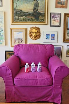 a living room with a purple chair and pictures on the wall above it, along with two bottles of hand sanitizers