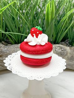 a red and white cake sitting on top of a table next to green plants in the background