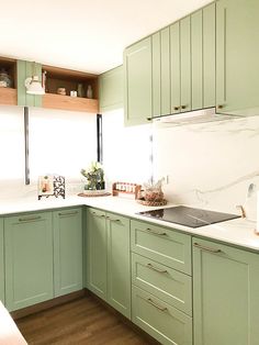 a kitchen with green cabinets and white counter tops