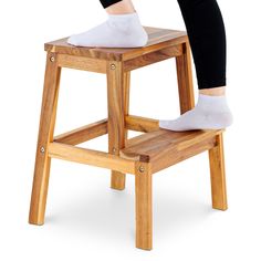 a person standing on a wooden stool with their legs crossed and feet up in the air