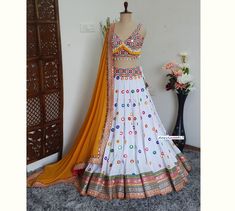 Made to Order/Measurement/Custom Order Lehenga - Color : White with Multicolor Embroidery - Fabric :  Rayon Cotton - Fully flared (8m)  lehenga skirt with multicolor border - Cotton Silk Deep V neckline blouse - Mustard Yellow Georgette dupatta with borders - Drawstring closure with designer Tassels - Can can attached PLEASE NOTE: BUYERS ARE RESPONSIBLE FOR ANY CUSTOMS AND IMPORT TAXES THAT MAY APPLY. Fabric Care : Dry Clean Only Disclaimer: Please note the photographs are taken by mobile camera V Neckline Blouse, Designer Tassels, Multicolor Embroidery, Georgette Dupatta, Mobile Camera, Lehenga Skirt, Indian Lehenga, Can Can, Embroidery Fabric