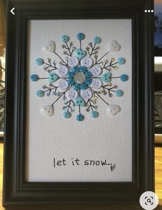 a framed artwork with buttons on it and the words let it snow written in black