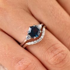 a woman's hand with a ring on it and a blue stone in the middle