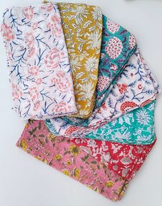 six different colored floral fabric pieces on a white surface