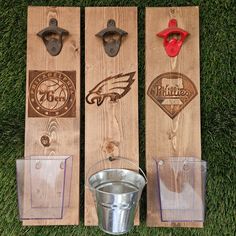 two wooden boards with metal buckets and philadelphia eagles logos on them, sitting in the grass