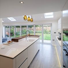 a kitchen with white counter tops and yellow pendant lights